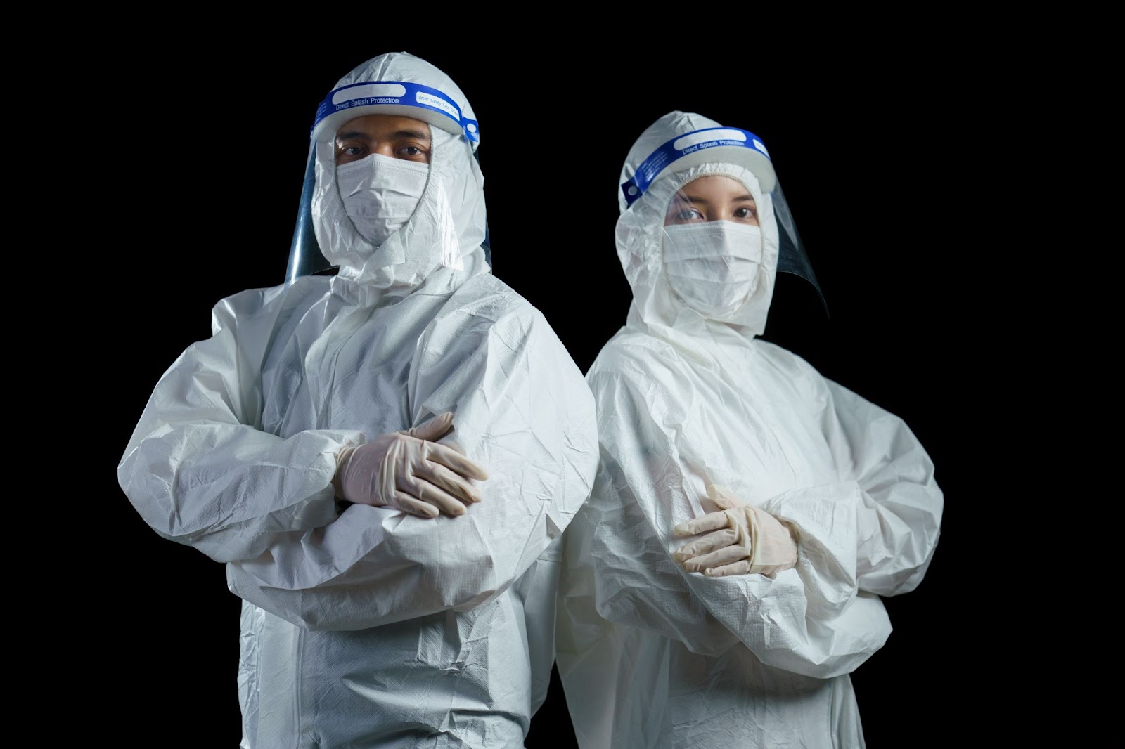Two individuals in protective gear standing against a black backdrop