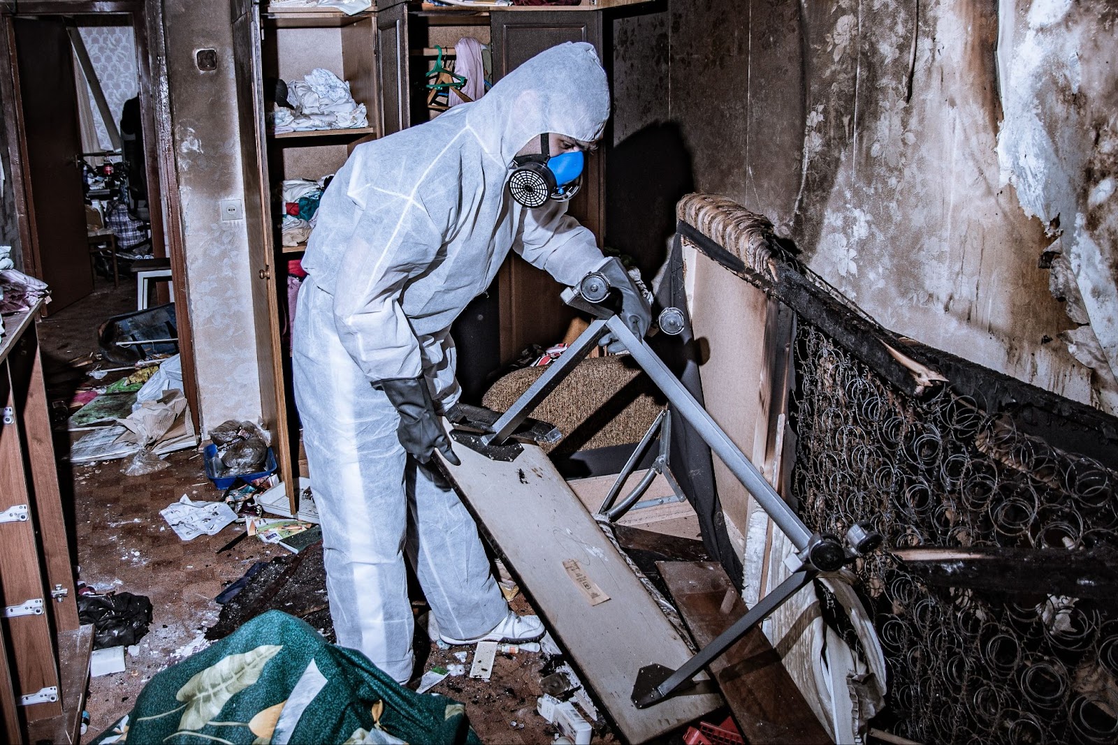 A person in a white protective suit cleans a room after a house fire, restoring it from fire damage