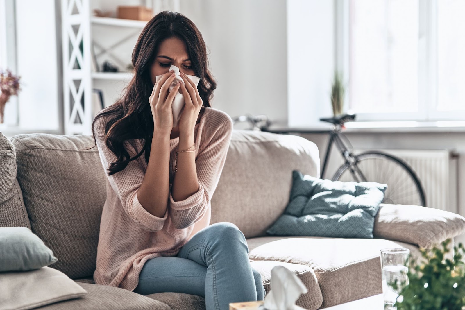 Woman with tissue on couch, likely due to mold allergies or exposure to mold spores