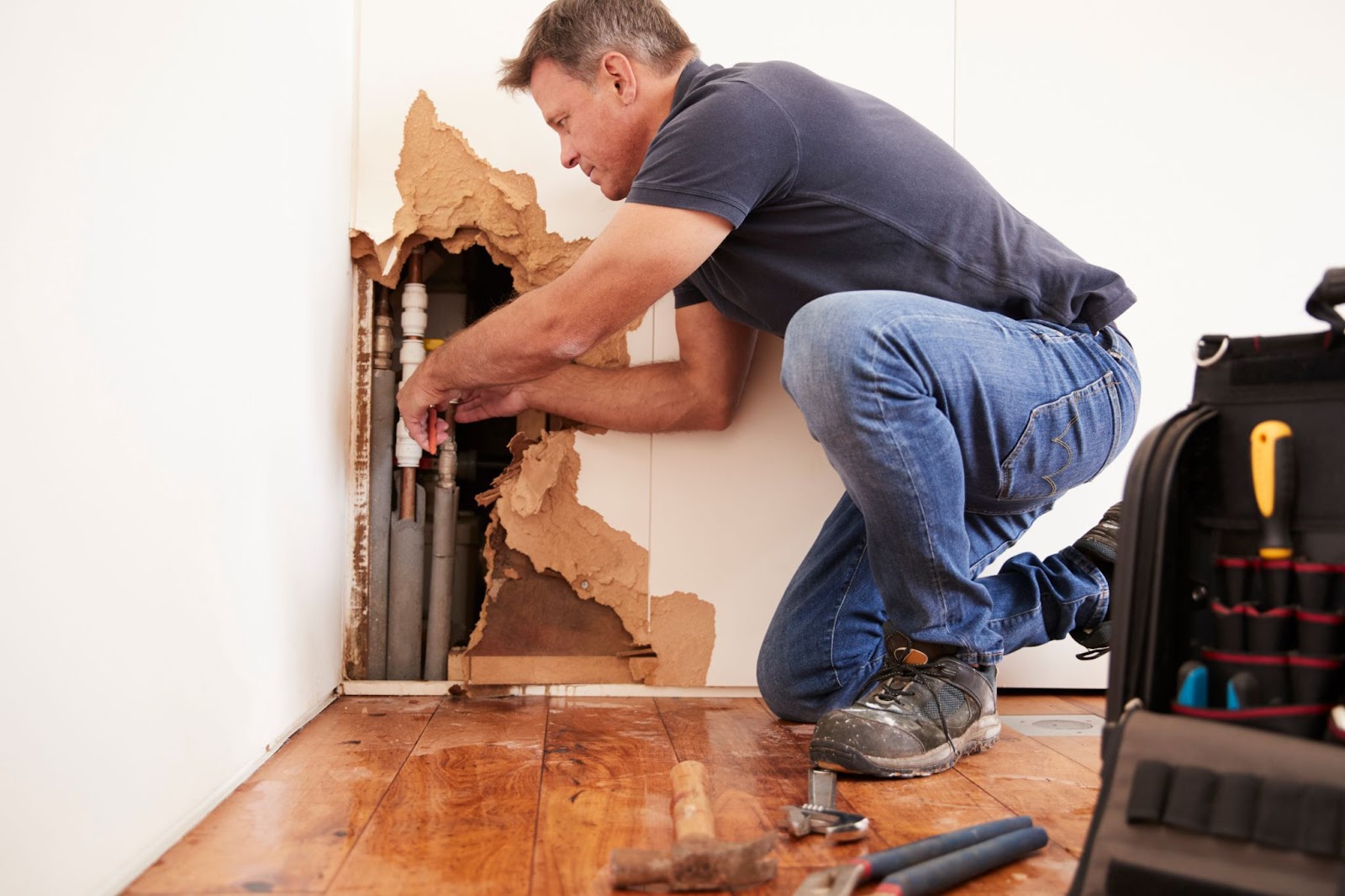 A professional repairs a wall hole, focusing on mold growth prevention as part of water damage restoration efforts.