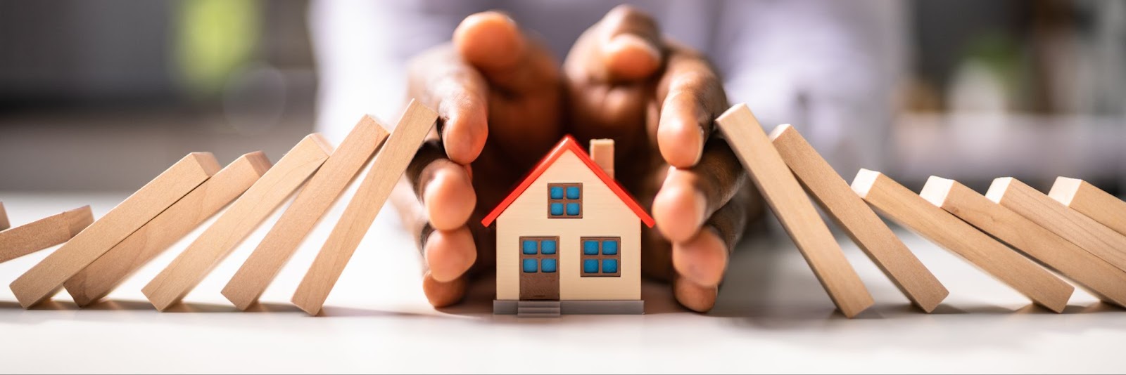 A person holds a wooden house and block, symbolizing restoration efforts after a house fire in Utah.