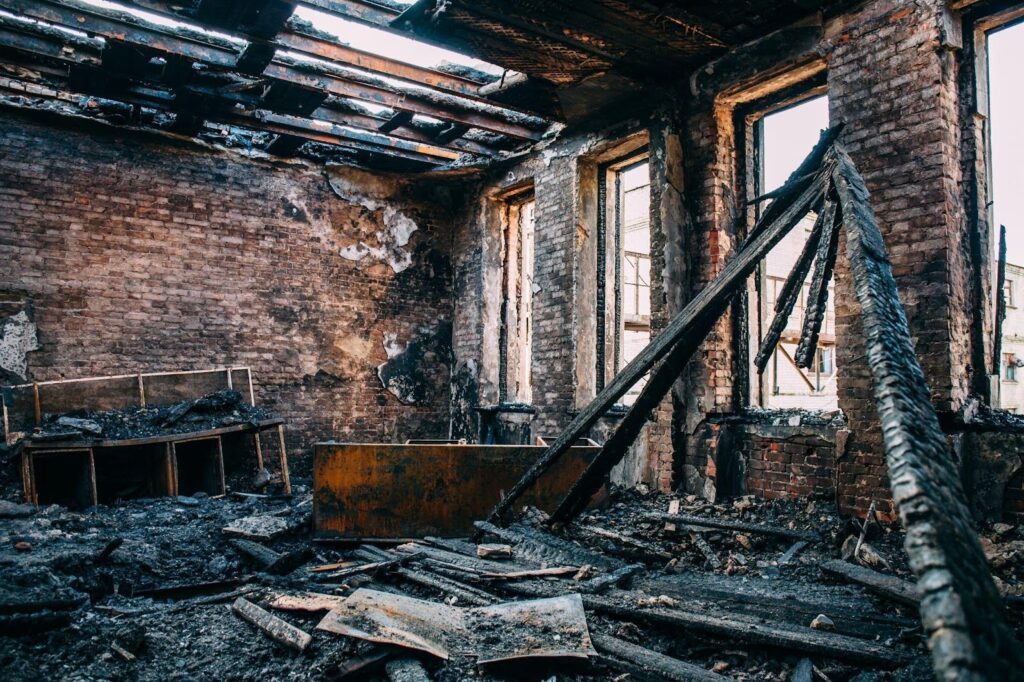 Fire-damaged building interior with blackened surfaces and debris