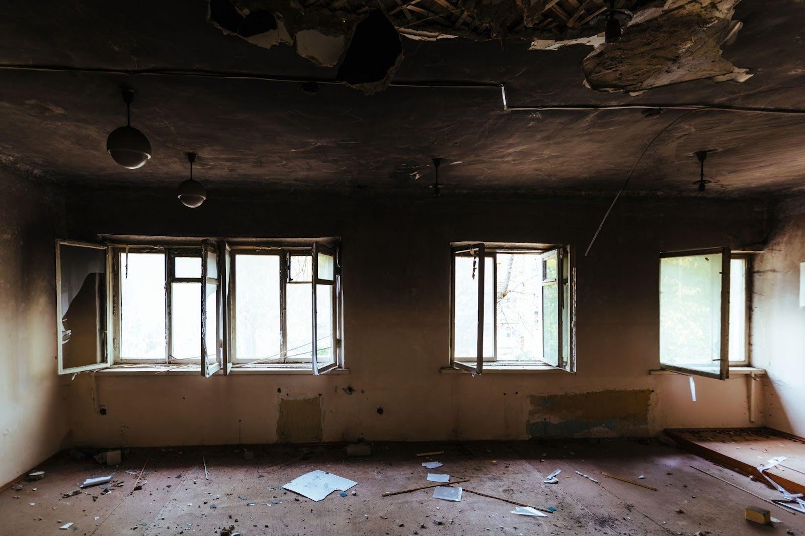 A damaged room with scattered debris and multiple broken windows reflecting a state of disarray