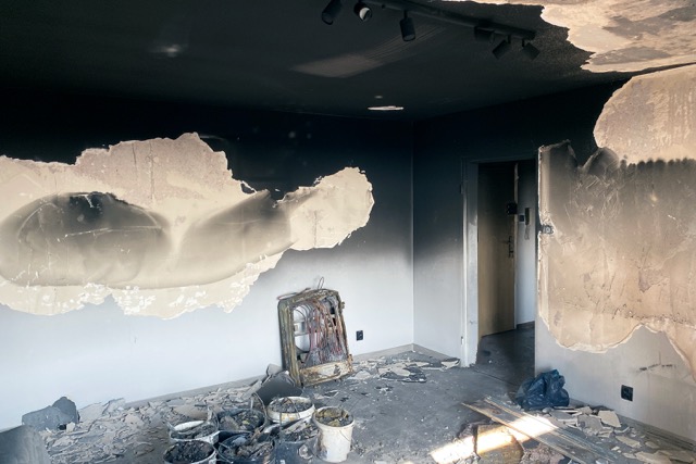 A smoke-damaged room with a mirror, highlighting the aftermath of a fire and the ongoing cleanup process.