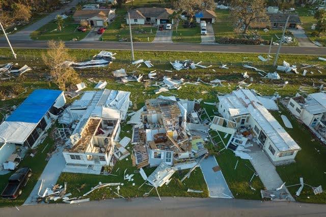 Aerial view of tornado aftermath showing severely damaged homes with debris scattered across lawns