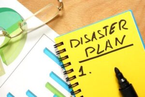 Yellow notebook labeled “Disaster Plan 1” with a black marker