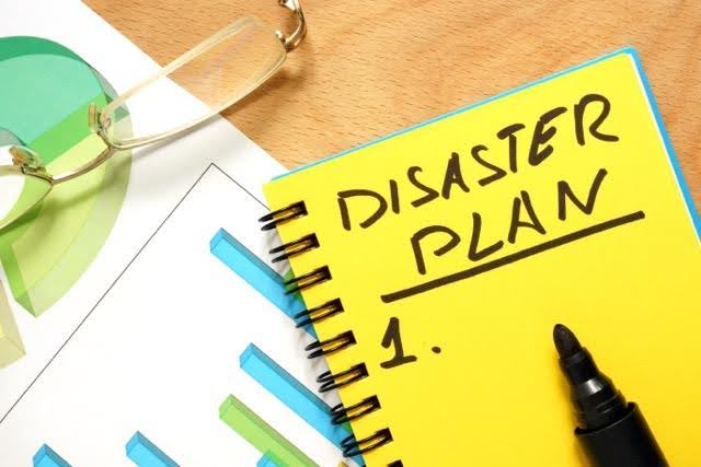 Yellow notebook labeled “Disaster Plan 1” with a black marker