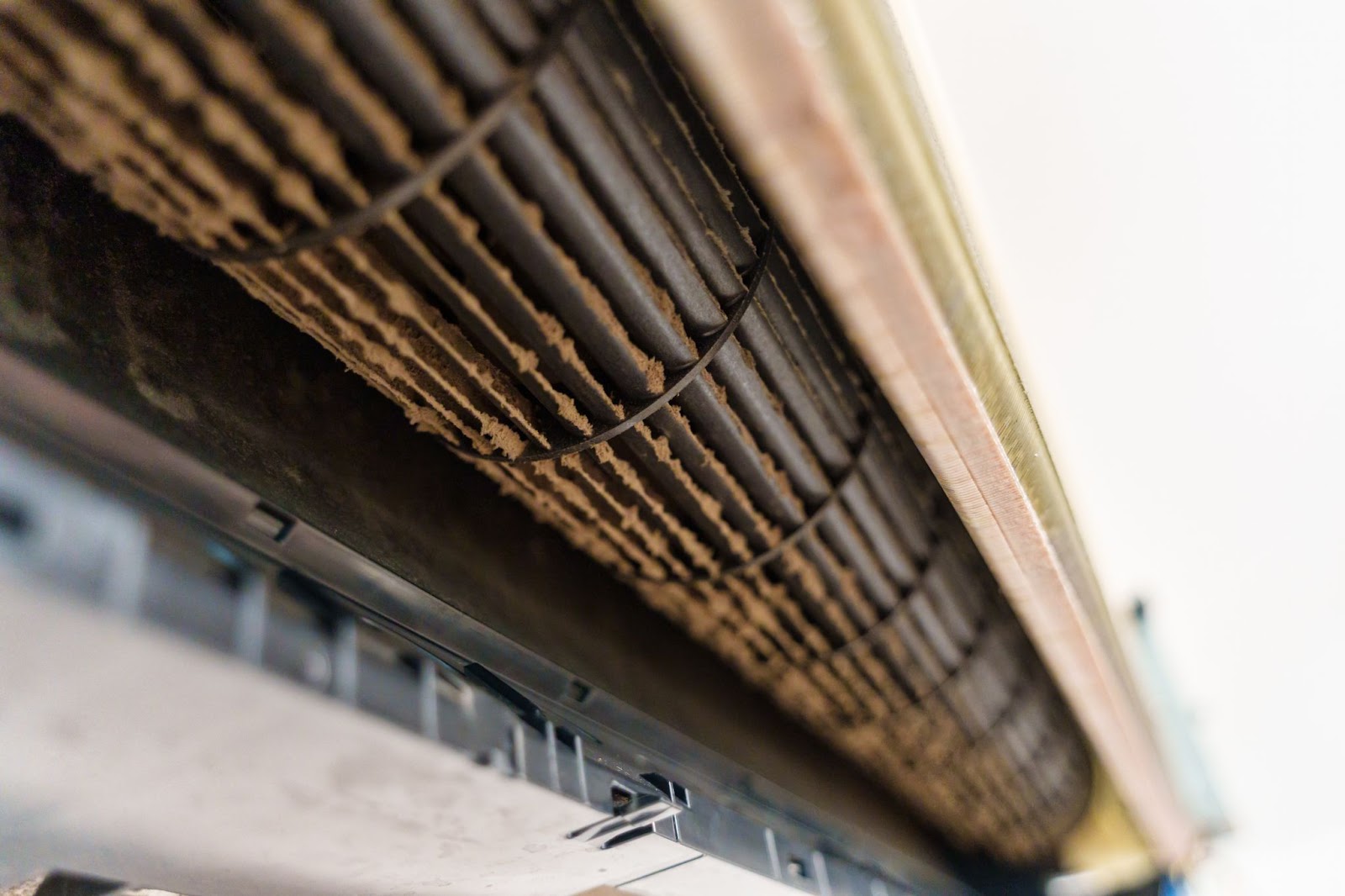 A close-up view of a heavily soiled air conditioner blower wheel, showing thick layers of dust and debris buildup on the fan blades.