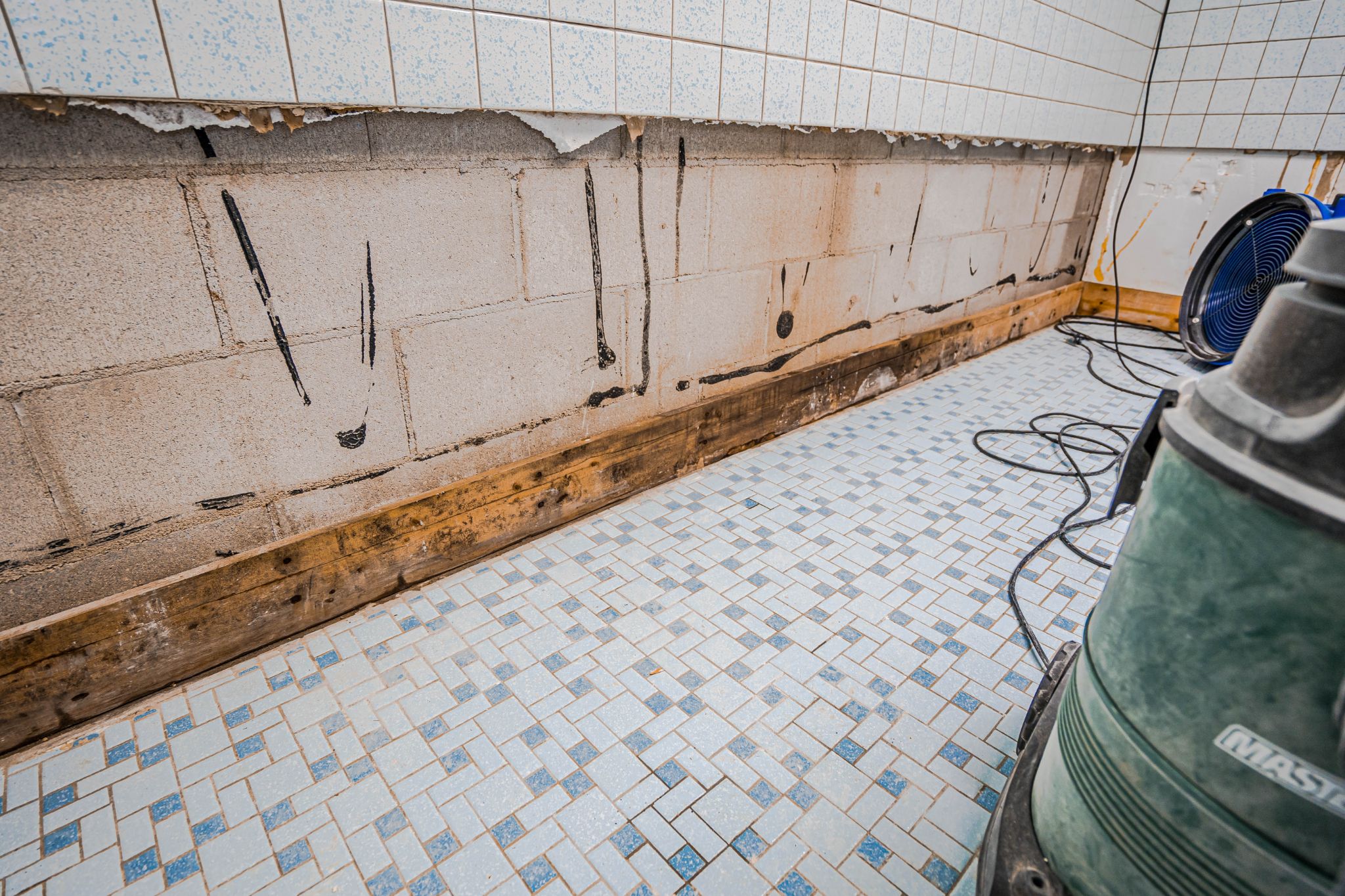 A room undergoing water damage restoration with exposed concrete blocks and drying equipment.