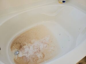 A white bathtub with heavy brown and orange stains around the drain.