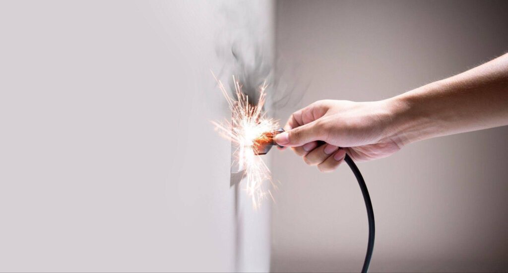 A hand with a sparkler illuminates a wall casting shimmering light and creating a festive atmosphere