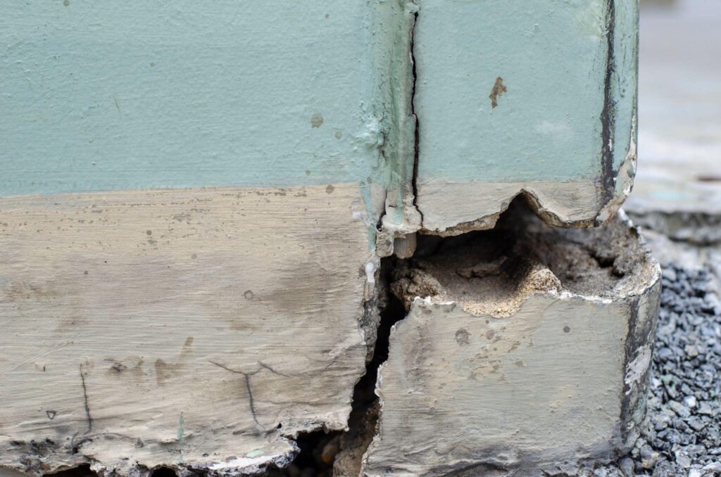 A damaged section of a building wall featuring a prominent hole exposing the materials inside