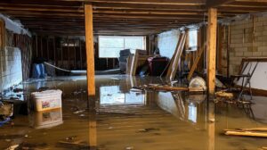 A flooded basement filled with debris and furniture illustrating significant water damage